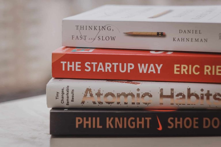 A close-up of four stacked books—Thinking, Fast and Slow, The Startup Way, Atomic Habits, and Shoe Dog—offering inspiration for anyone seeking success through grants funding or foundation funding.