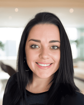 Meet our Experts: A woman with straight, blonde hair wearing a light blue denim shirt stands indoors in a modern, well-lit room with large windows.